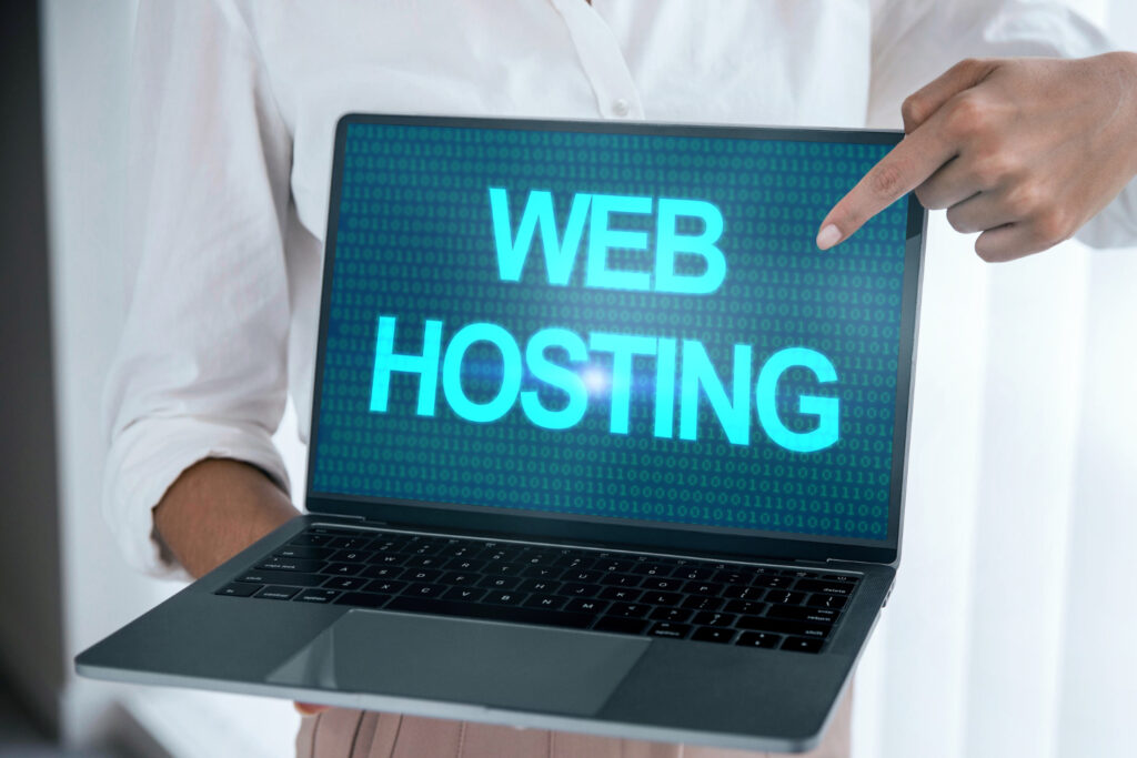 Person pointing at a laptop screen displaying 'WEB HOSTING' in bold letters, representing the best web hosting services in UAE