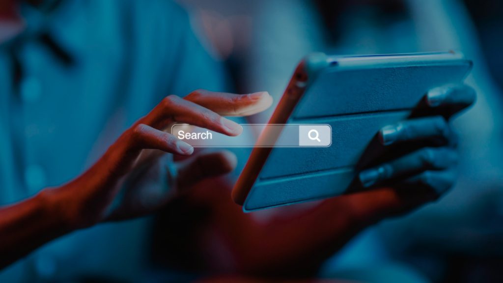 Person using a tablet with a digital search bar overlay, symbolizing online search and SEO.